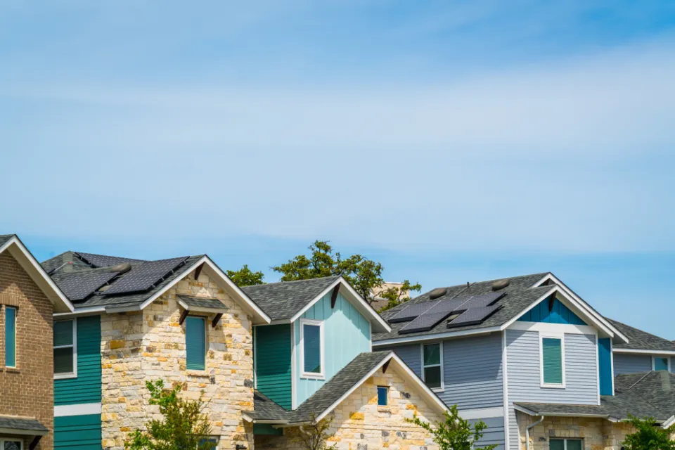 A row of homes, some brightly colored, on a sunny day in Austin, Texas.